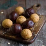 Plain and chocolate coated protein balls on a wooden board.