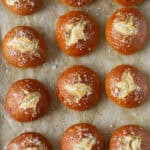 Homemade pretzel buns on parchment paper.