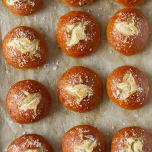 Homemade pretzel buns on parchment paper.