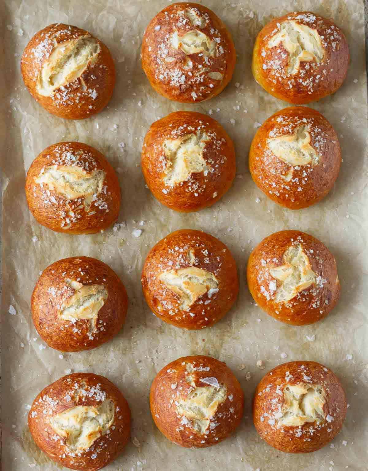 Baked pretzel buns on parchment paper.