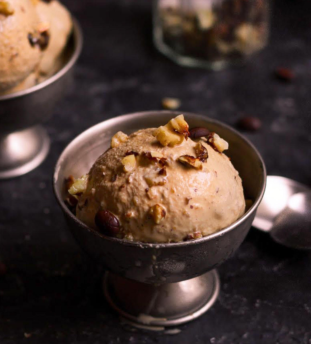 a scoop of ice cream with walnuts on top in an ice cream cup.