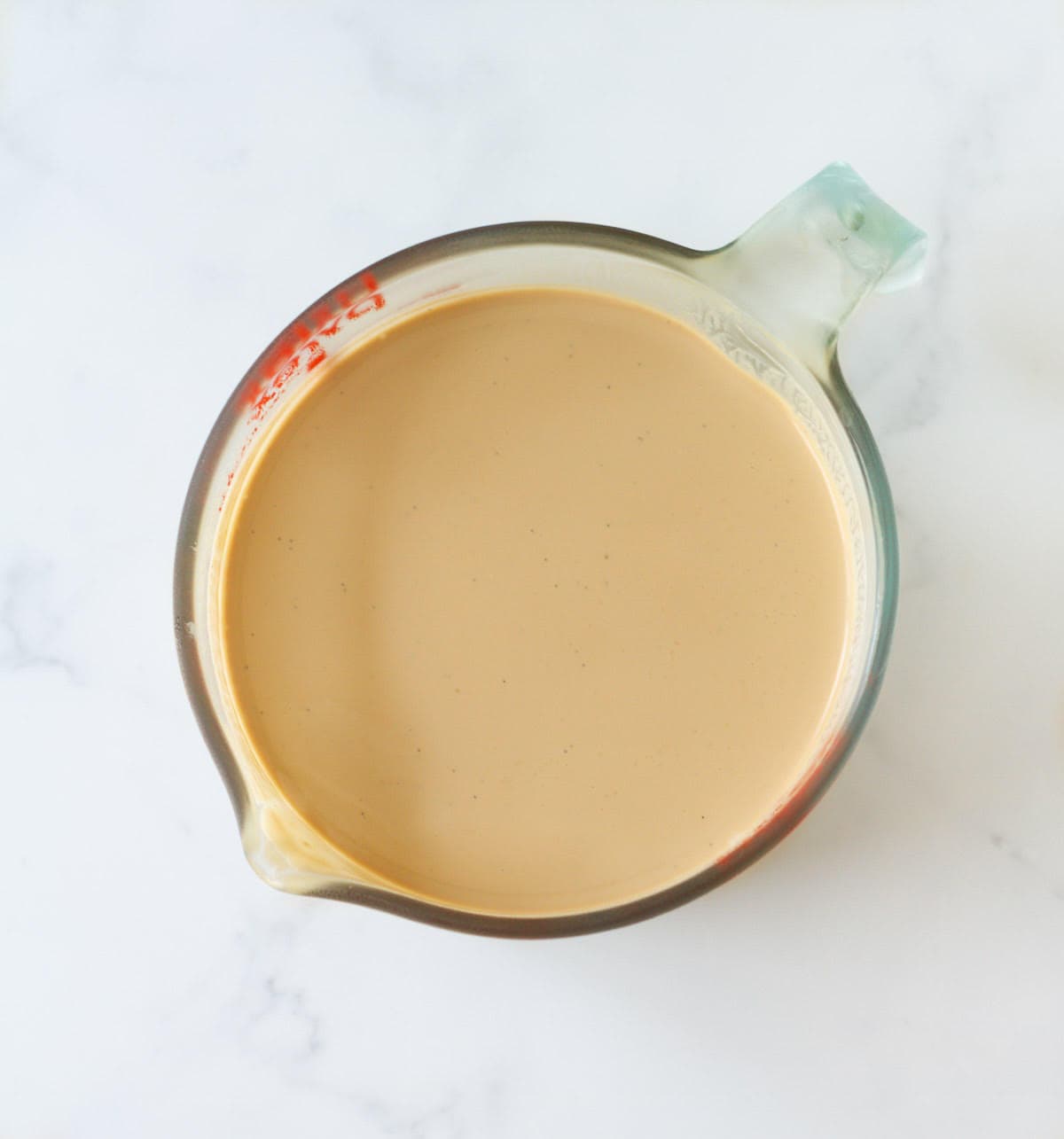 Strained coffee mixture in a measuring cup.