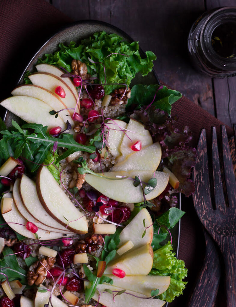 sliced apples and pomegranate on top of quinoa and salad greens.
