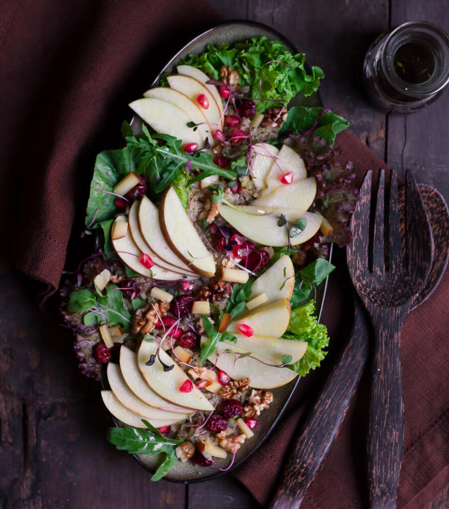 apple walnut salad in an oval platter with wooden serving spoons.