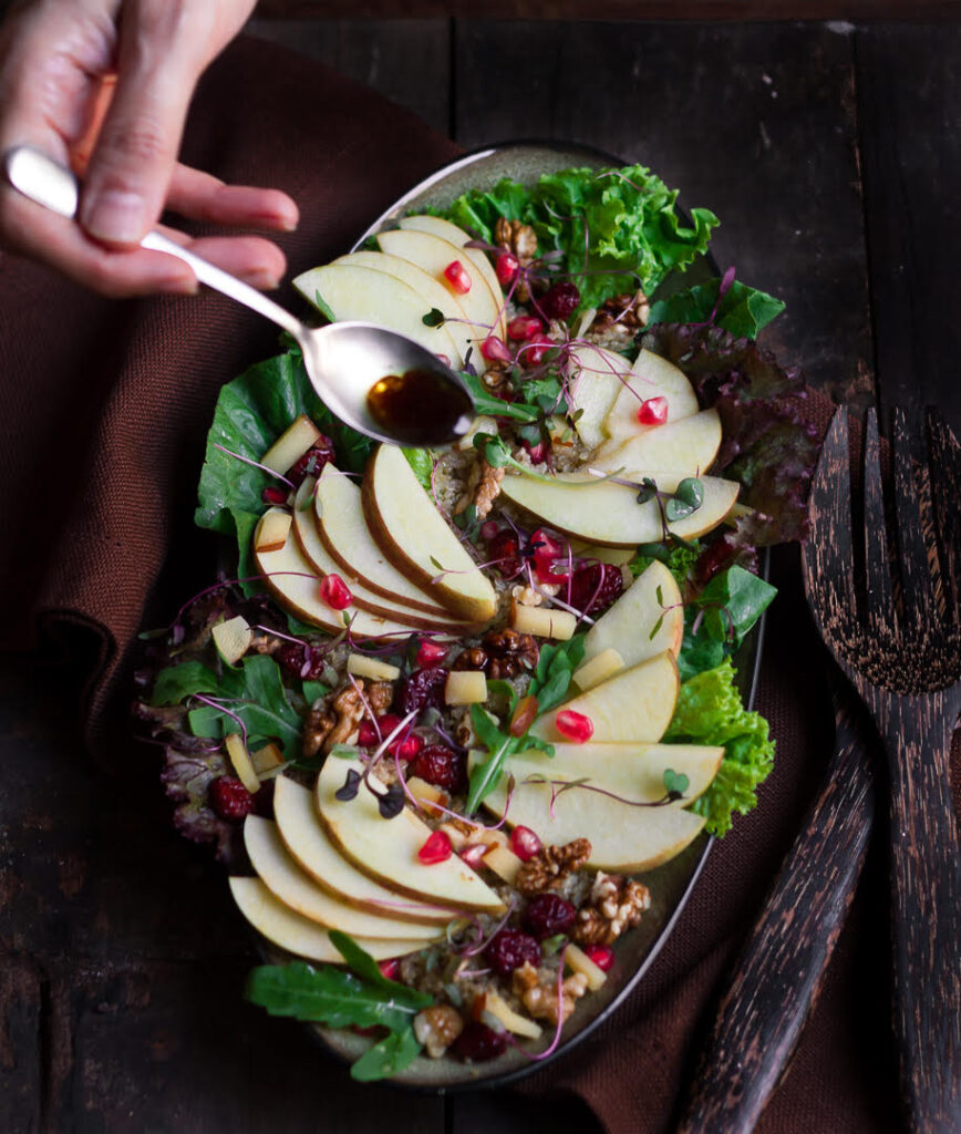 Spooning the balsamic vinaigrette over the Apple Walnut Salad.