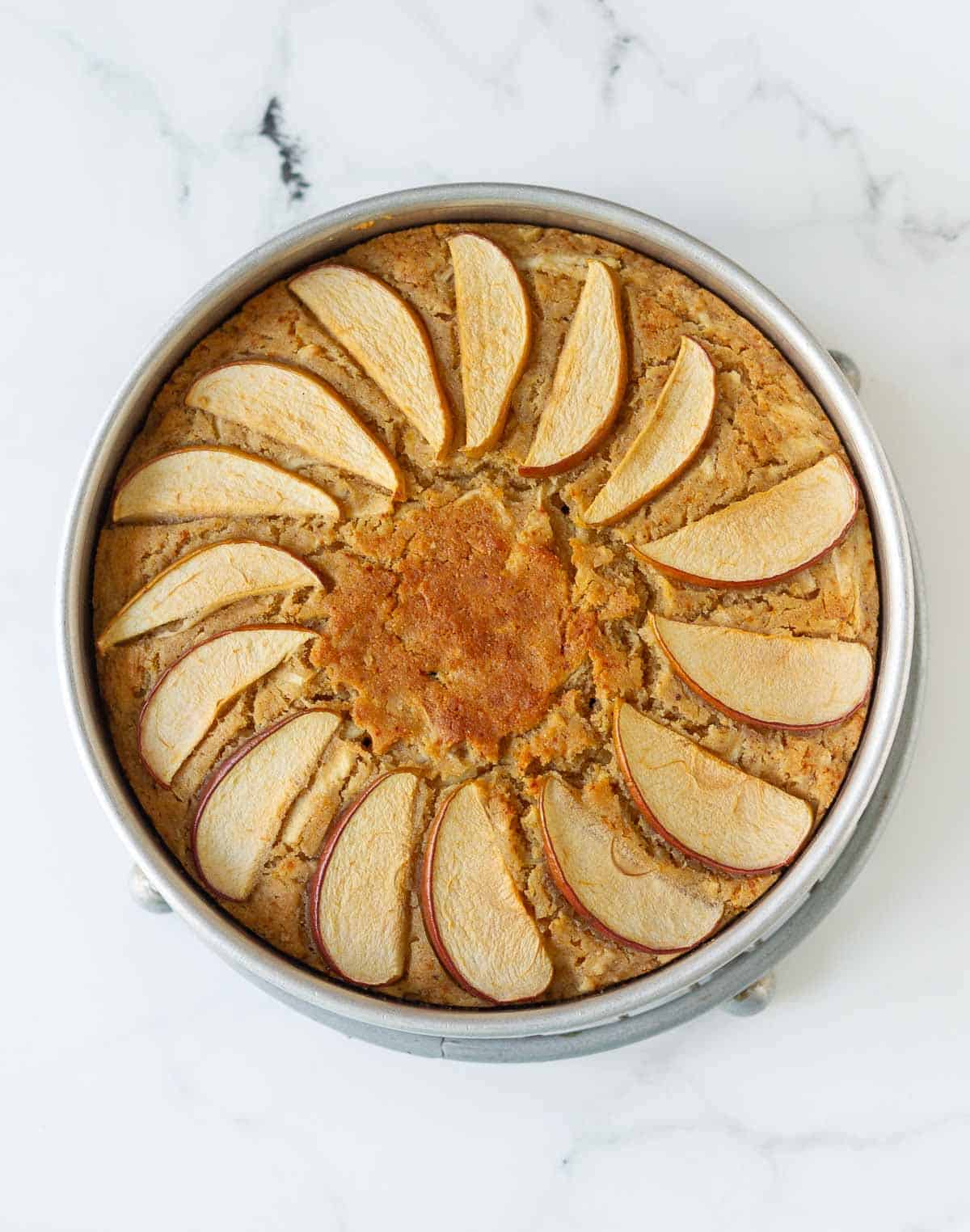 Baked chai spiced apple cake in a round cake tin.