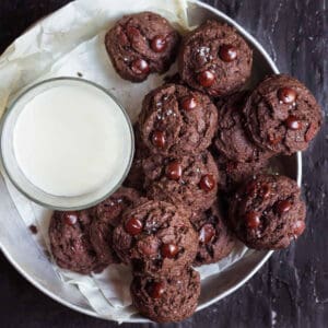 A plate of chocolate cookies with a glass of milk.