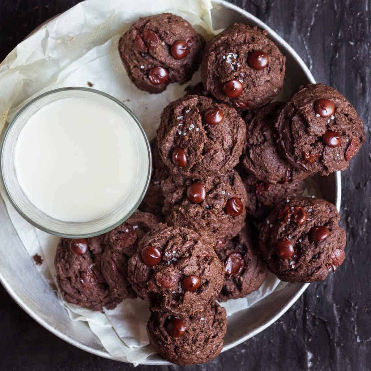 A plate of chocolate cookies with a glass of milk.