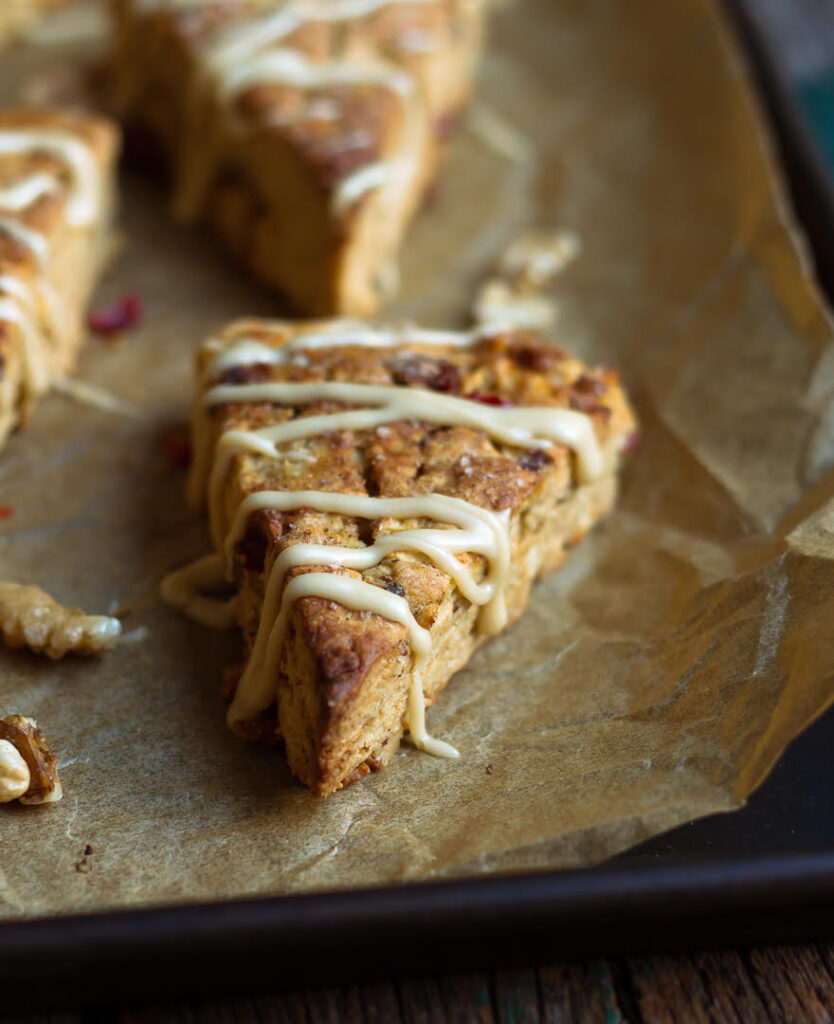 apple scone with maple glaze on a parchment lined tray.