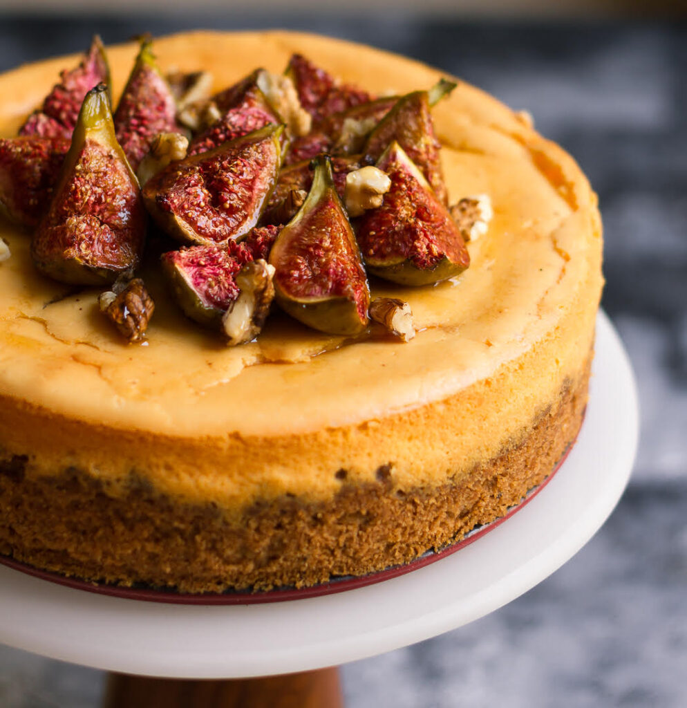 cheesecake with figs and walnuts on a cake stand.
