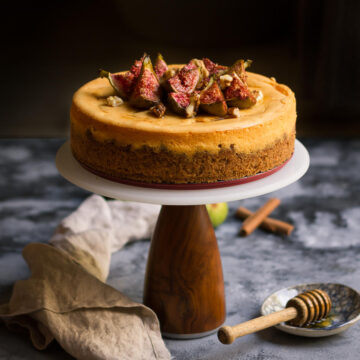 Cinnamon Cheesecake with figs on top on a cake stand.