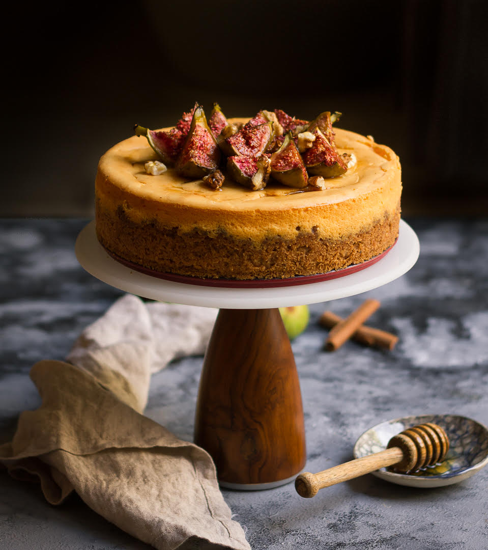 Cinnamon Cheesecake topped with figs on a cake stand.