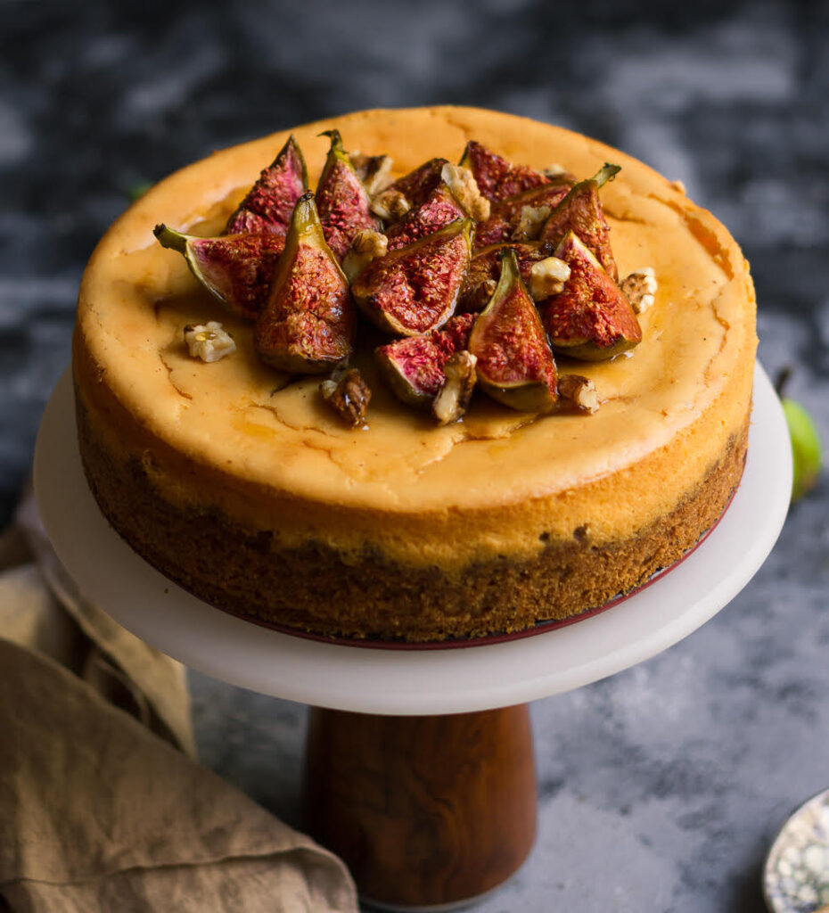 cinnamon cheesecake with figs, walnuts, and honey on a cake stand.