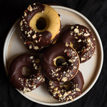 chocolate dipped pumpkin donuts on a plate.