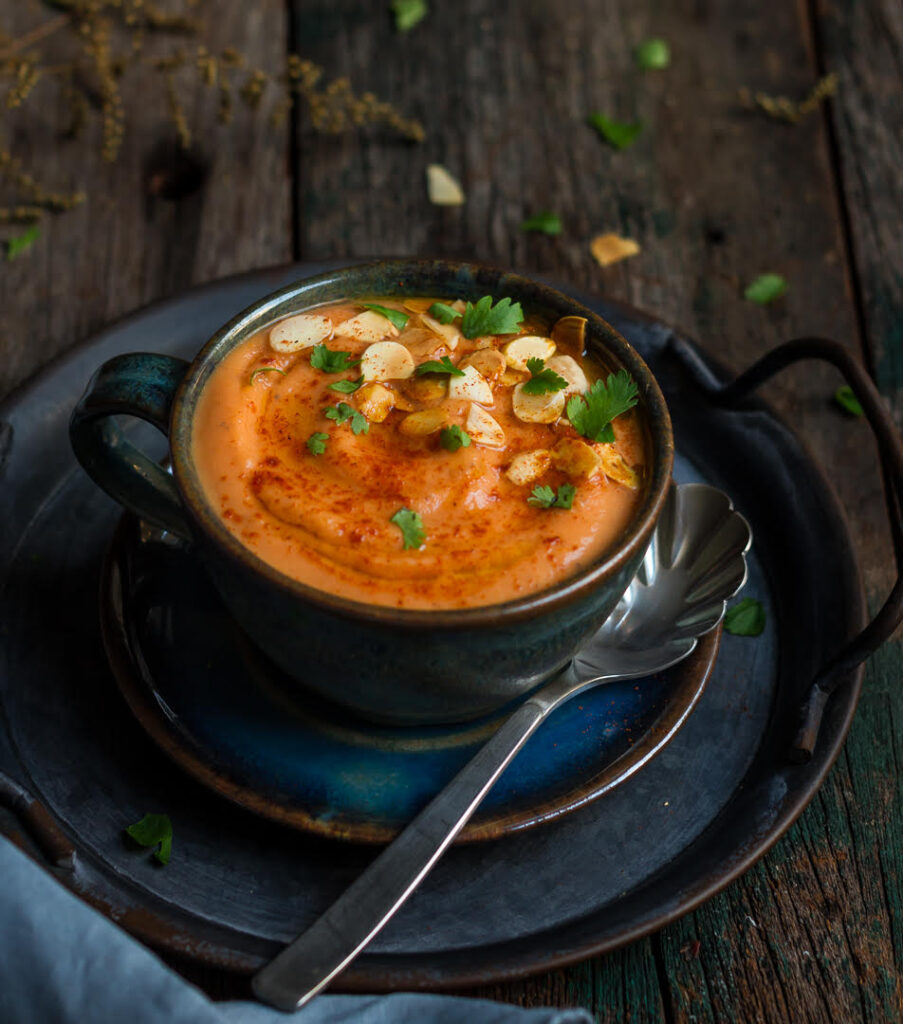 Soup in a bowl with a spoon on the side on a small plate and tray.