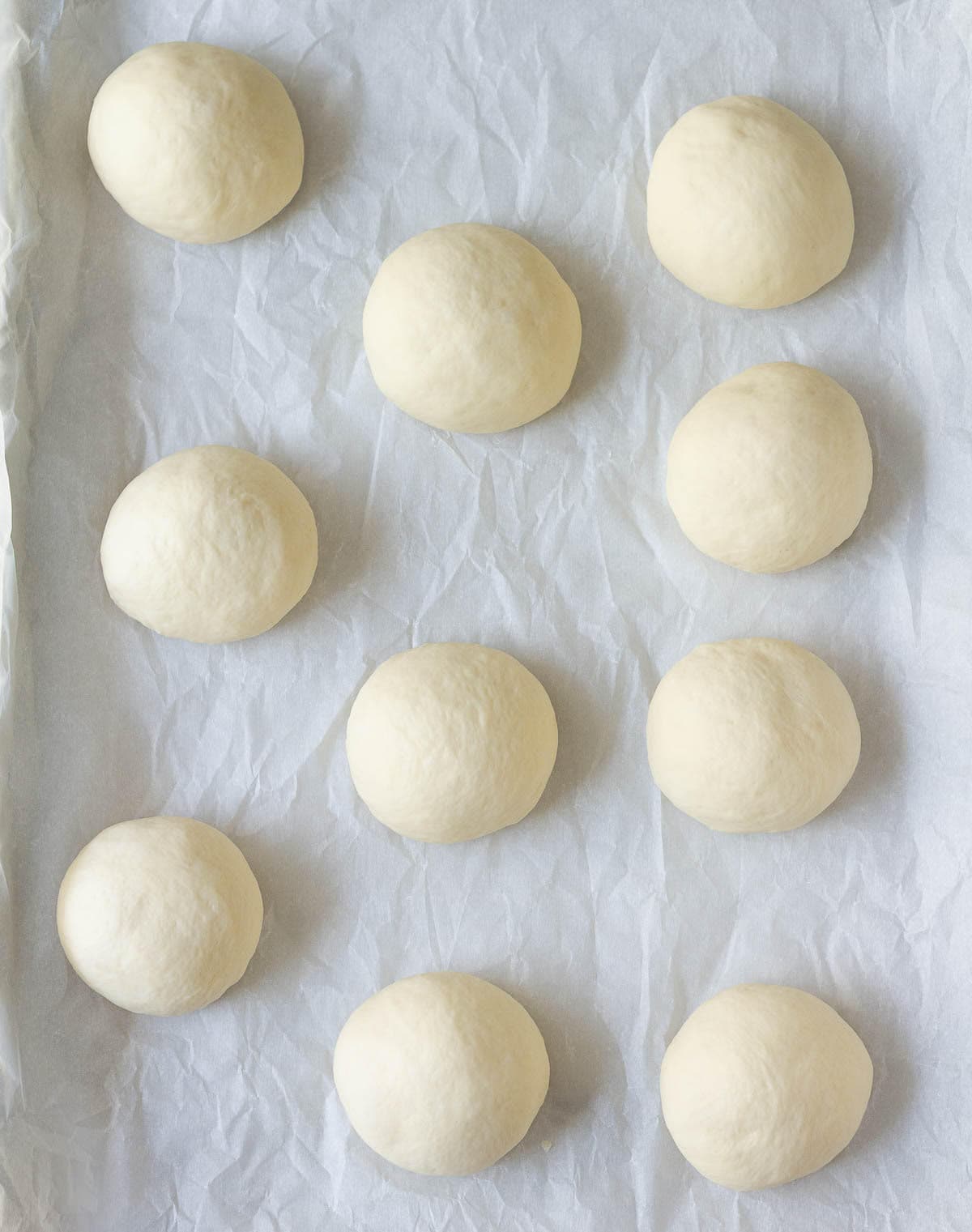 Dough balls on a baking tray lined with parchment paper.