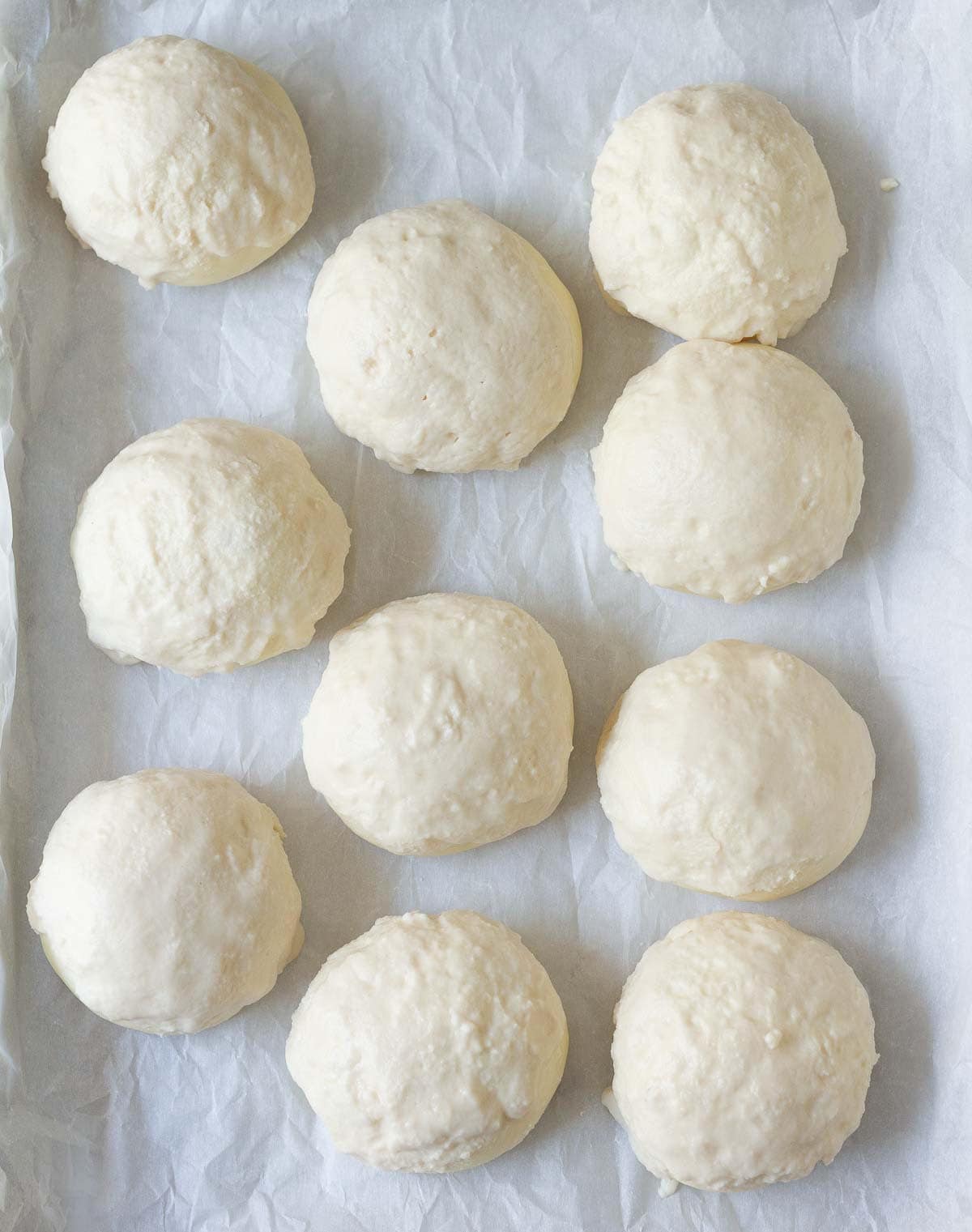 Dough balls coated with rice flour paste on a baking tray with parchment paper.