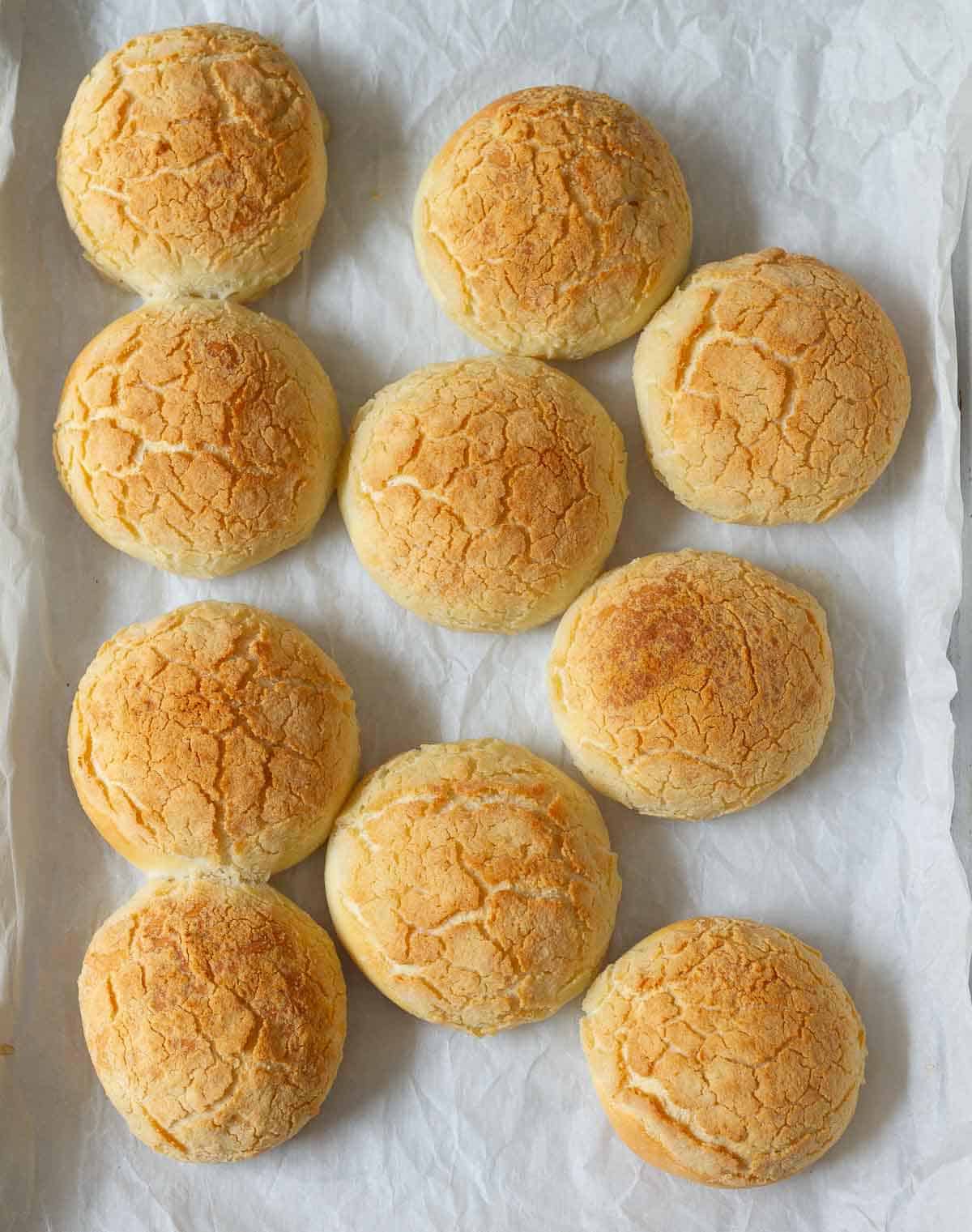Baked Tiger bread rolls on a baking tray with parchment paper.
