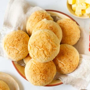 Bread rolls in a napkin lined bowl with butter on the side.