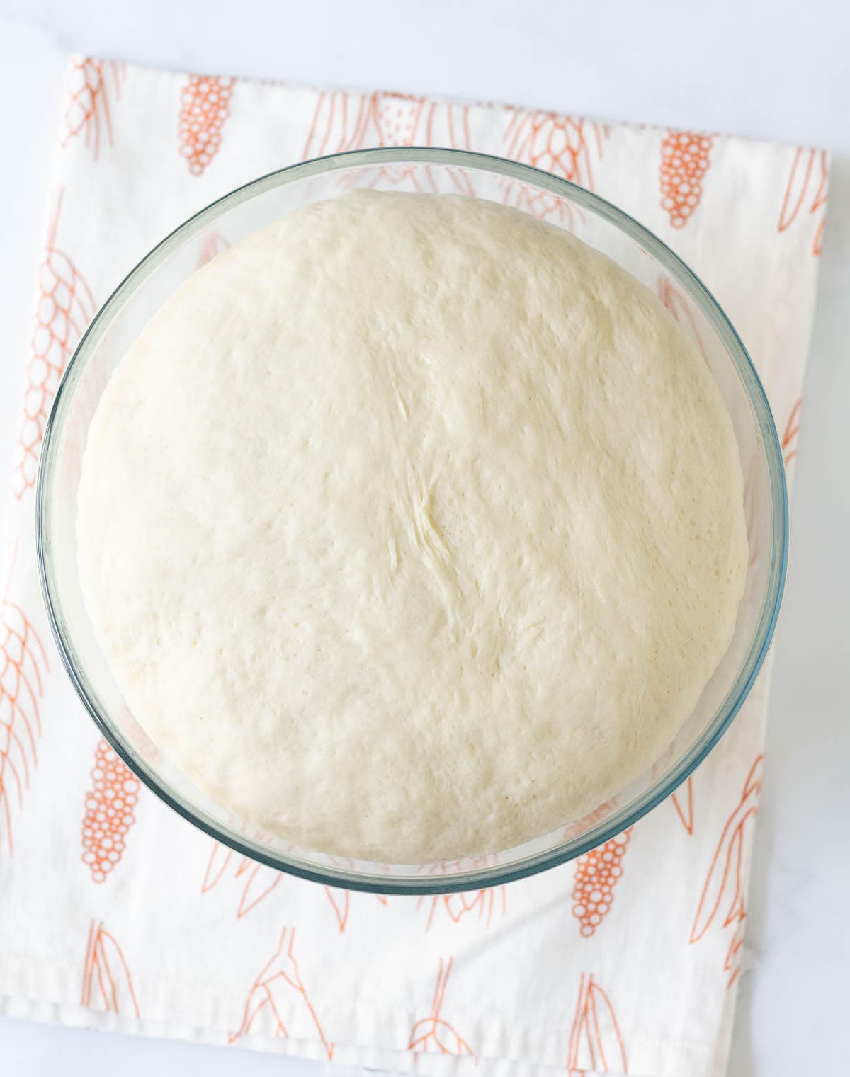 Proofed dough in a glass mixing bowl.