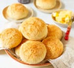 Bread rolls stacked in a bowl with butter on the side.