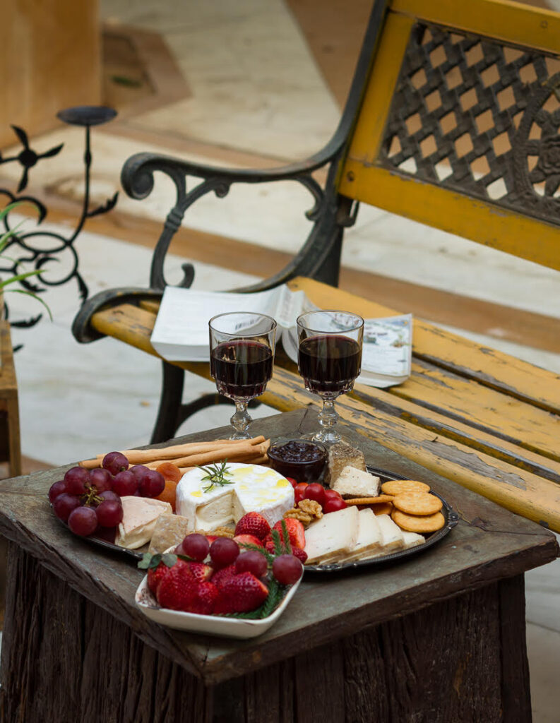 cheeseboard kept outdoors with wine with a bench and book