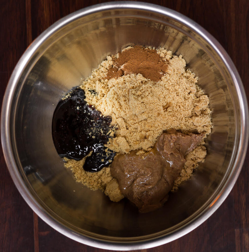 Ingredients for no bake gingersnap balls in a metal mixing bowl.