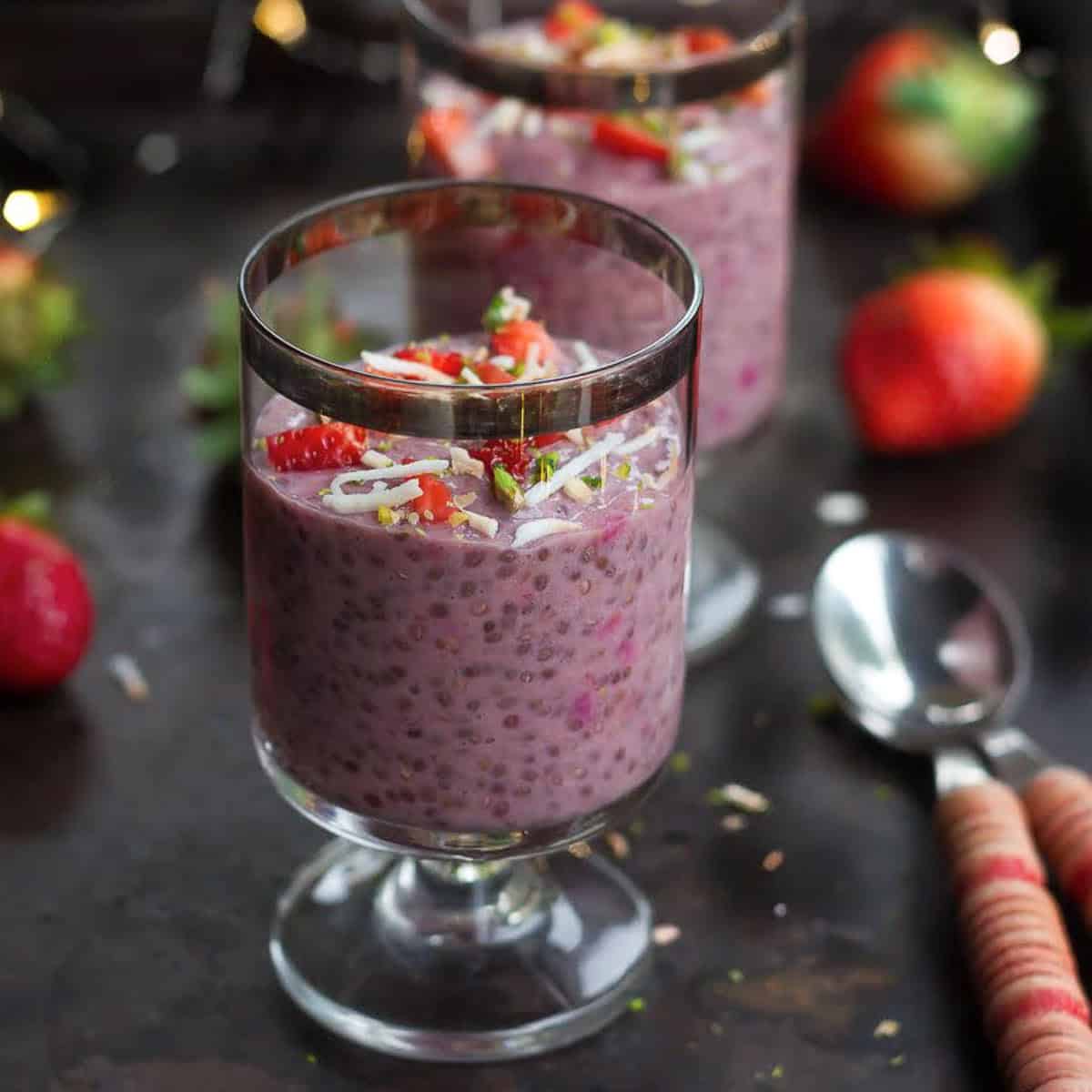 strawberry chia pudding in a dessert cup with 2 spoons next to it.