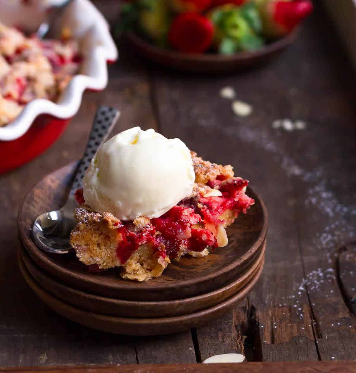 strawberry cake on a wooden plate with a scoop of vanilla ice cream.