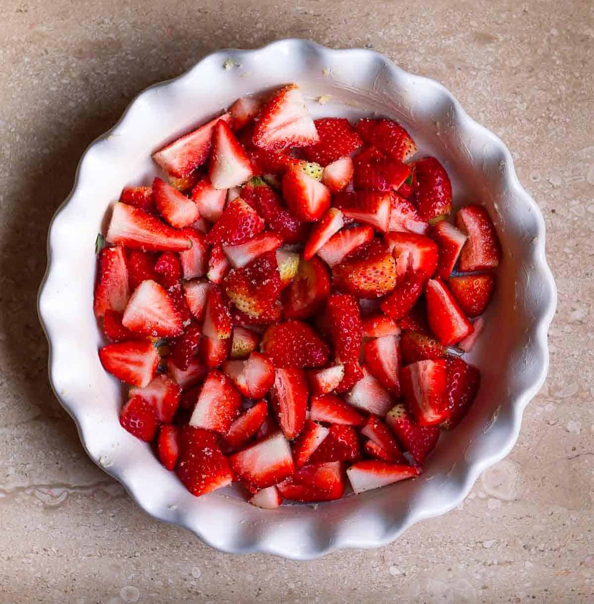 Chopped strawberries tossed with sugar in a baking dish.