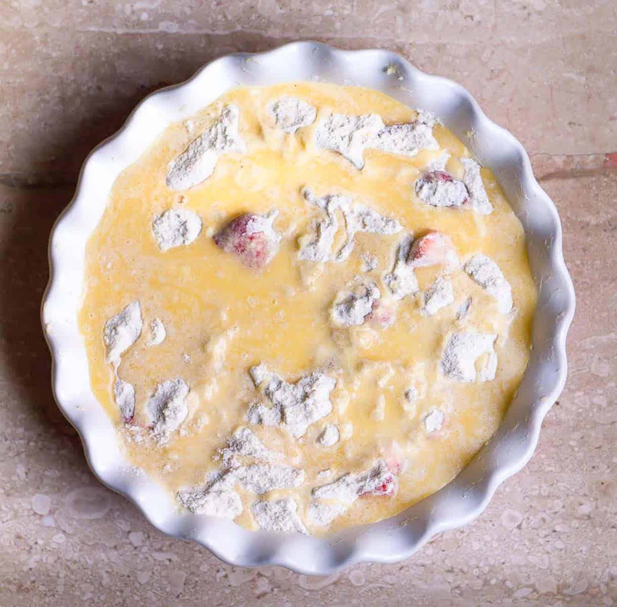 Dry ingredients for the cake topped with milk and butter in the baking dish.