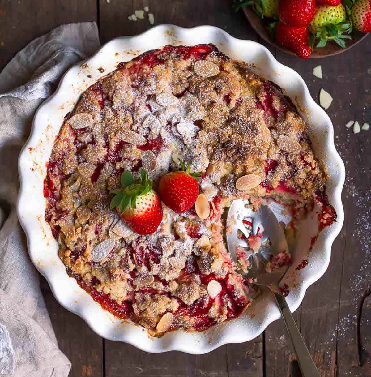 strawberry dump cake with a serving spoon in a baking dish with a slice taken out.