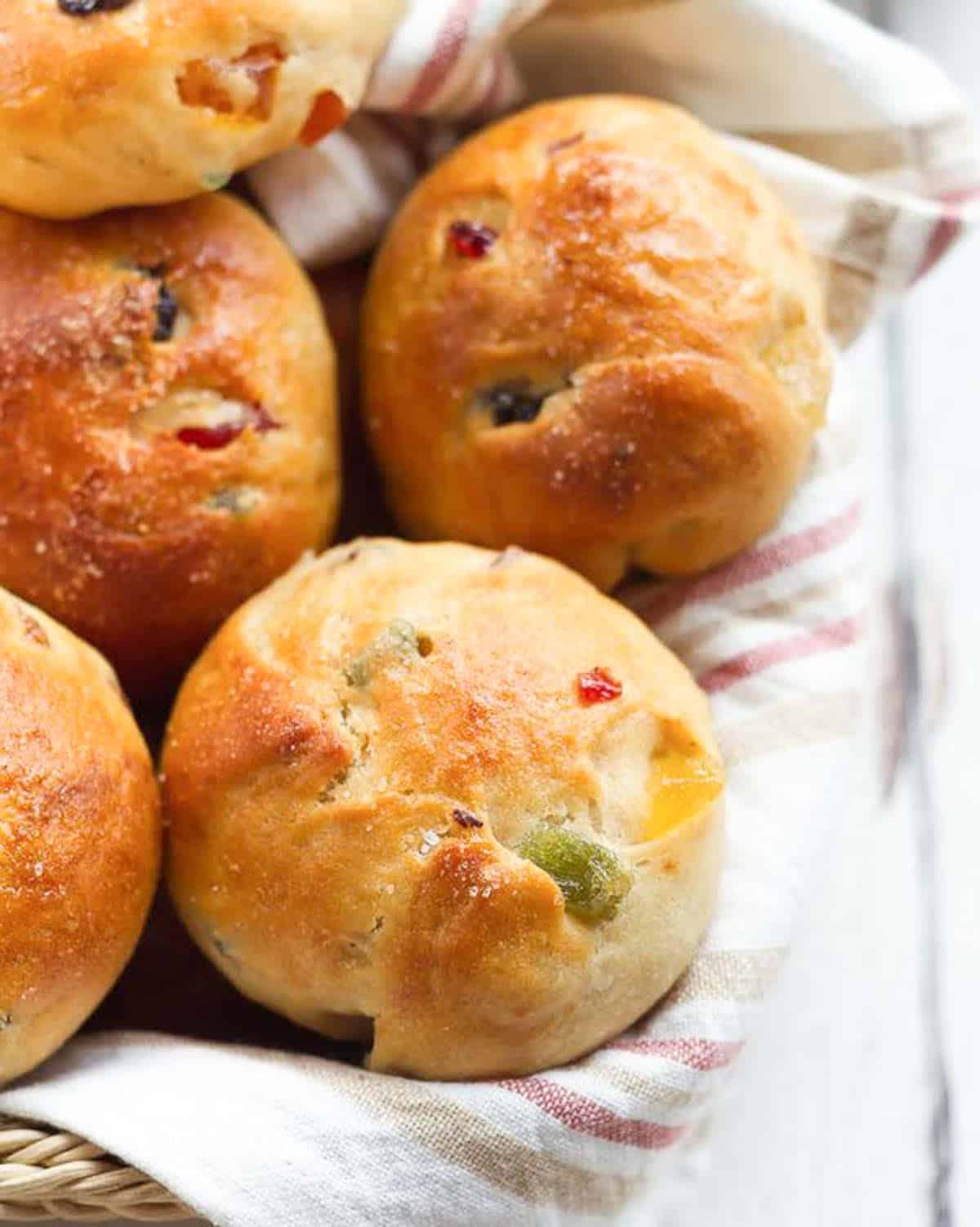 Bread rolls with tutti frutti in a napkin lined basket.