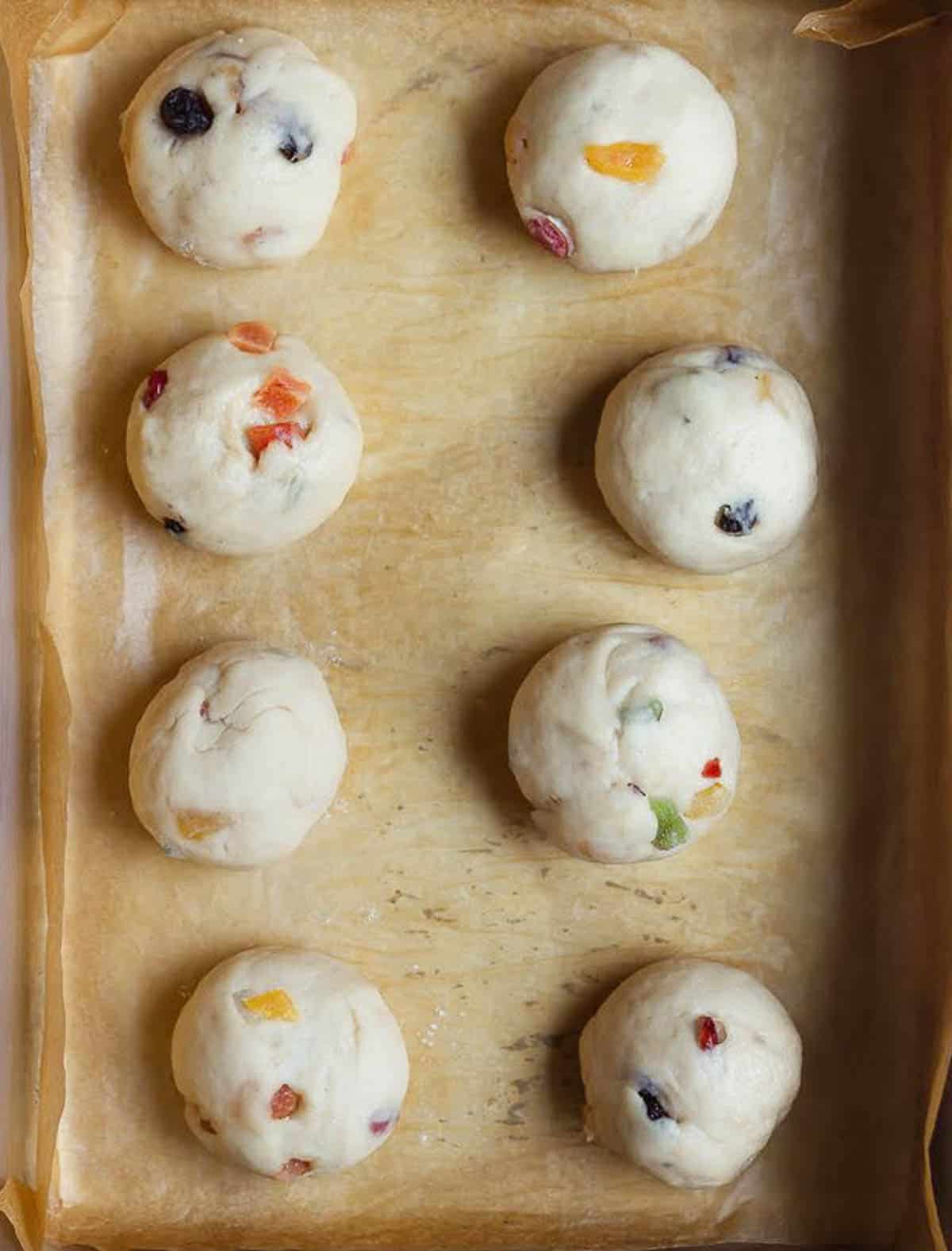 Bun shaped dough balls on parchment-lined tray.