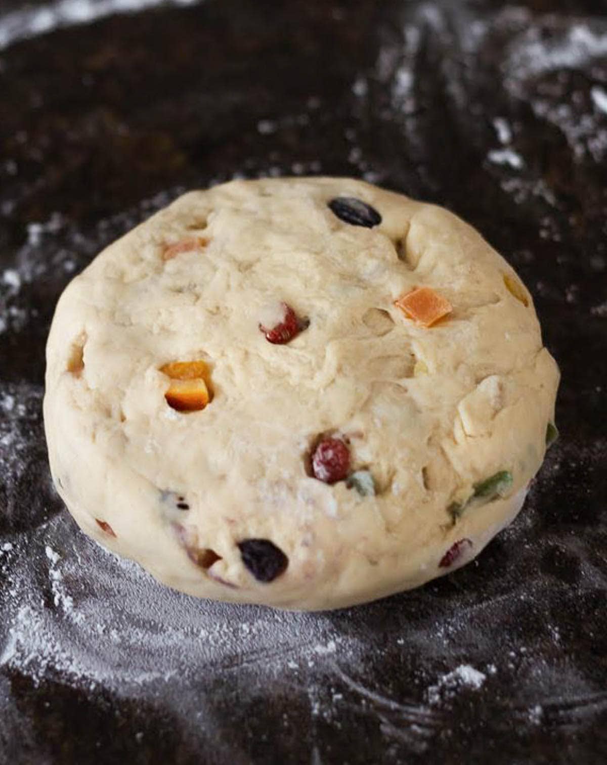 Dough with tutti frutti on a floured surface.