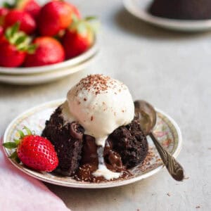 Chocolate lava cake with vanilla ice cream on top on a plate with a spoon.