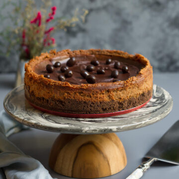 Espresso Cheesecake with chocolate covered coffee beans on a cake stand.