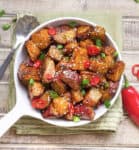 Sweet glazed sweet potatoes with sesame seeds in a white pan.