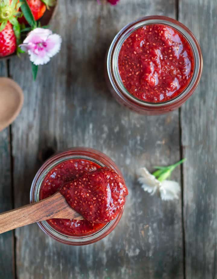 A spoonful of strawberry chia jam on top of a jar of jam to show the texture.