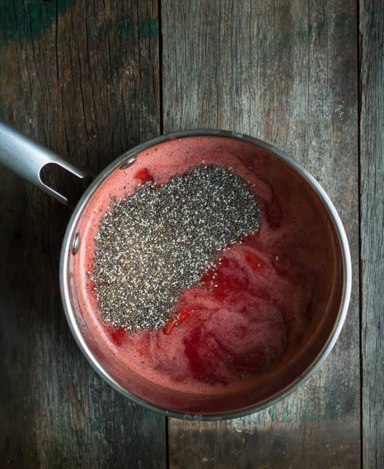 Pureed strawberry mixture with chia seeds in a stainless steel saucepan.