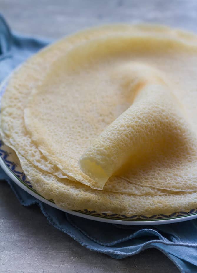 Crepes stacked a plate with one folded to show texture.