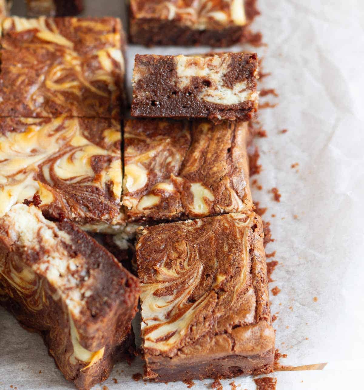 Brownies with cheesecake swirl on parchment paper.