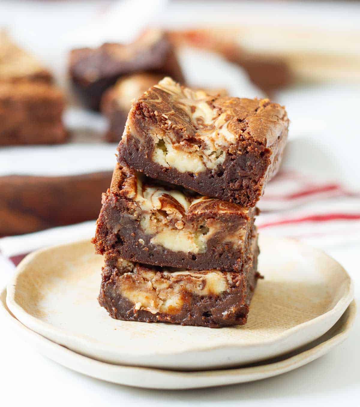 A stack of 3 brownies on a stack of 2 plates.