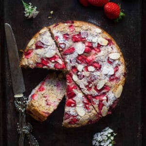 strawberry jam cake on a black tray with one slice kept down to show the texture.