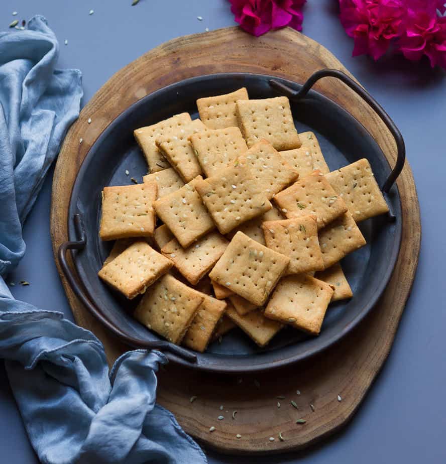 sweet mathri on a gray metal plate on a wooden board.