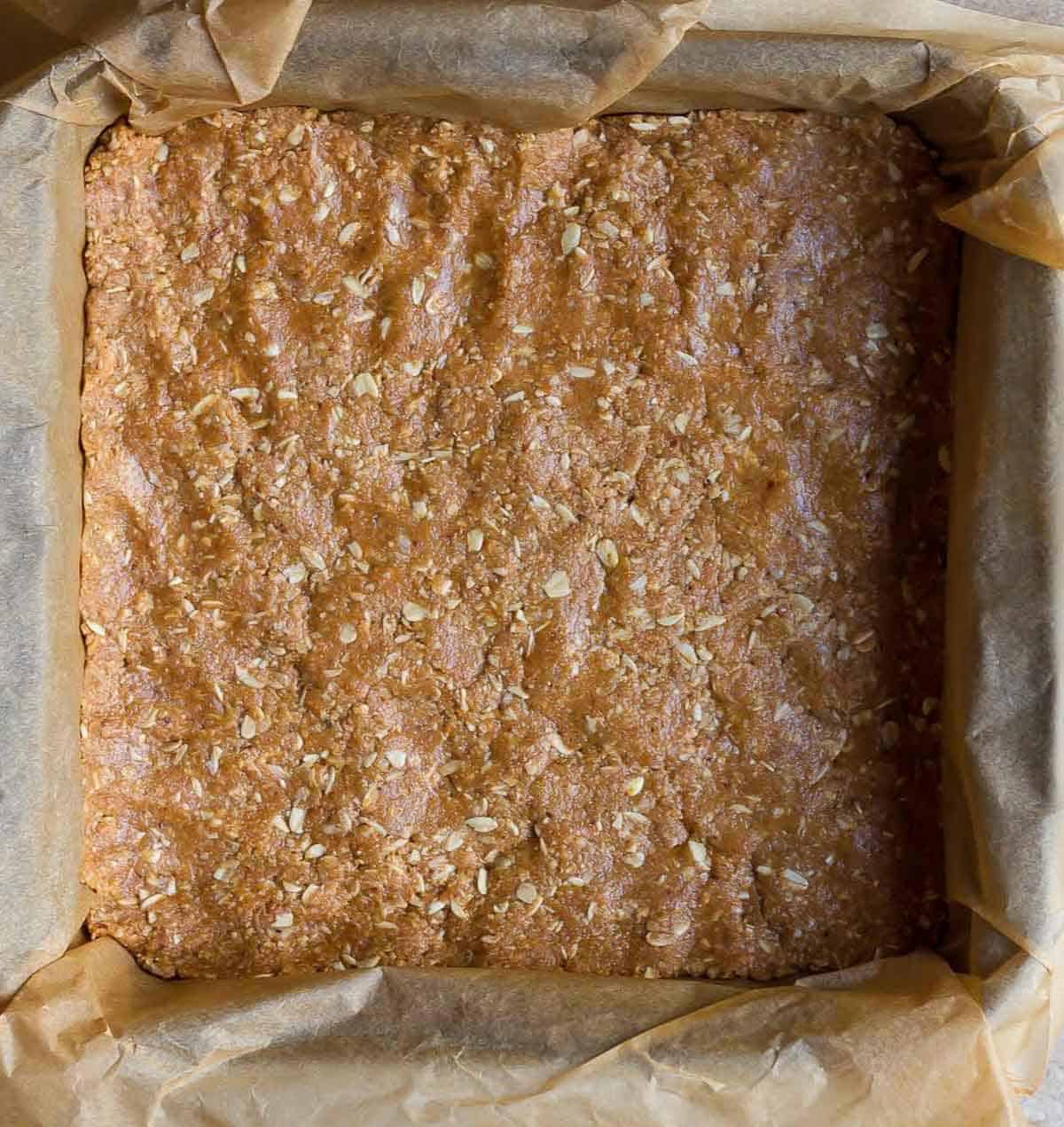 oatmeal base on parchment paper in a square pan.