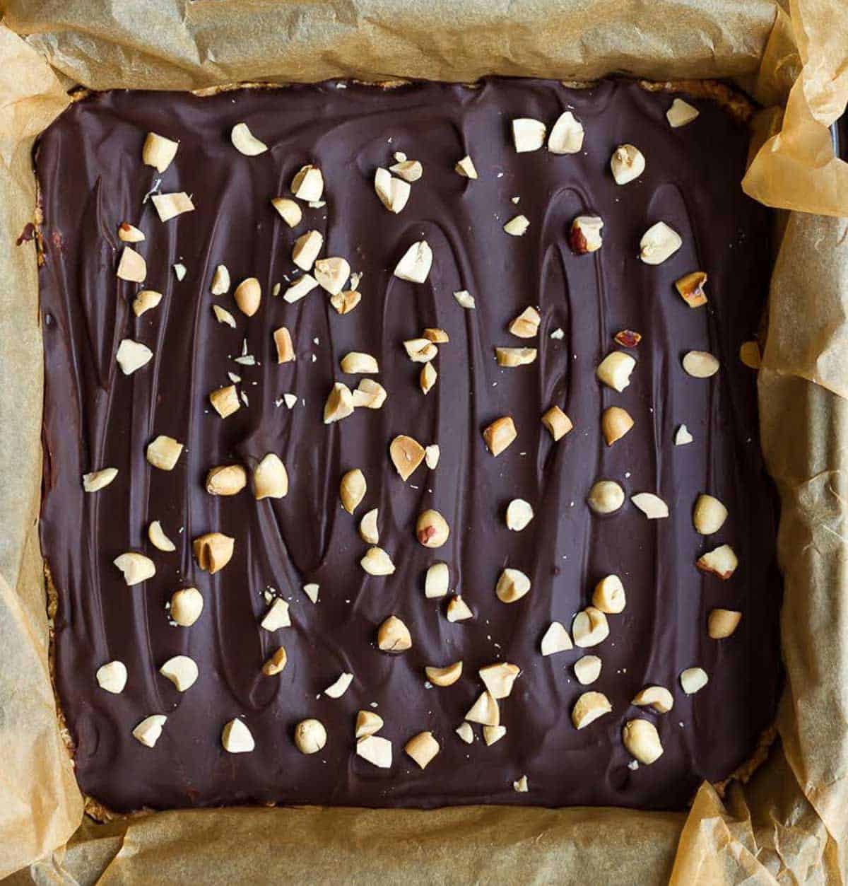 No-bake oatmeal bars topped with chocolate and peanuts in a pan.