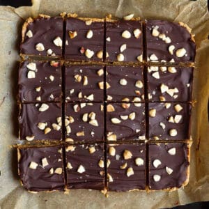 Chocolate peanut butter oatmeal bars cut into 16 squares on parchment paper.