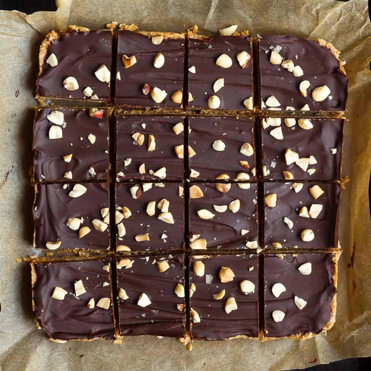 Chocolate peanut butter oatmeal bars cut into 16 squares on parchment paper.