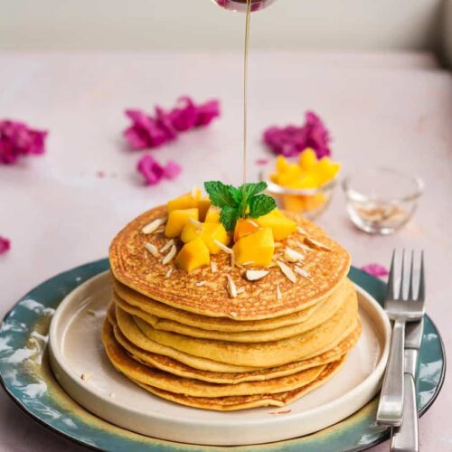 A stack of mango pancakes with a drizzle of maple syrup.